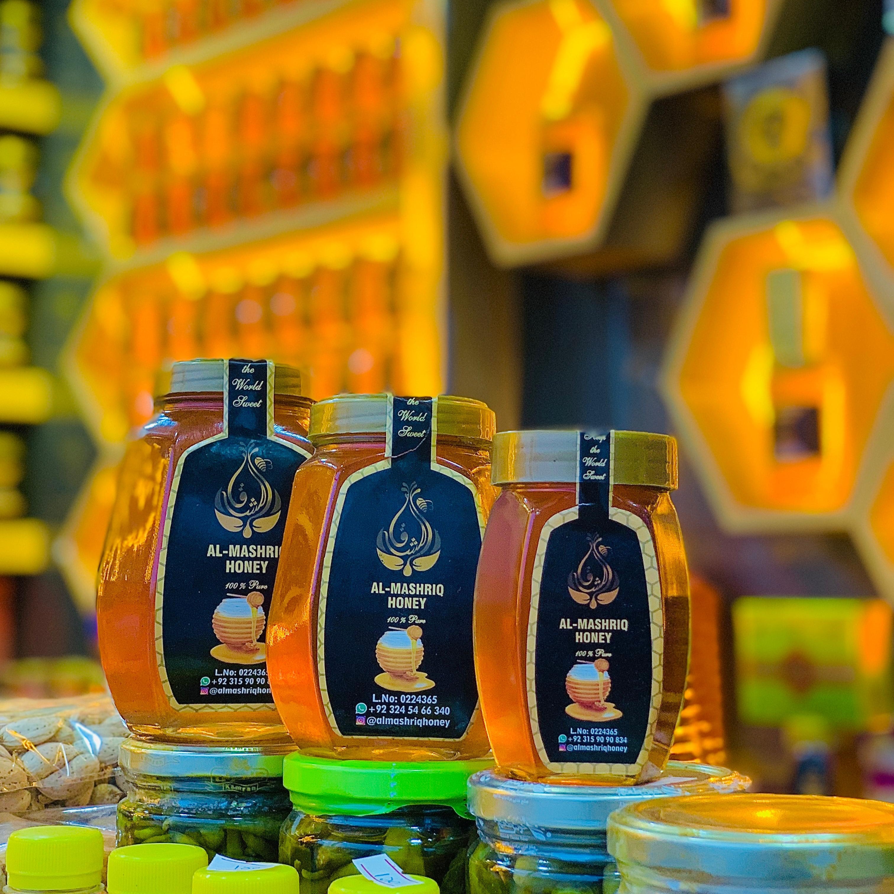 Jars of honey with visible labels against a blurred background of honeycomb shapes.